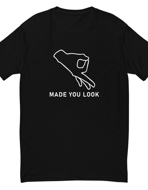 Load image into Gallery viewer, Black t-shirt that shows a drawn hand with the thumb and index finger forming  a circle and a caption of made you look.
